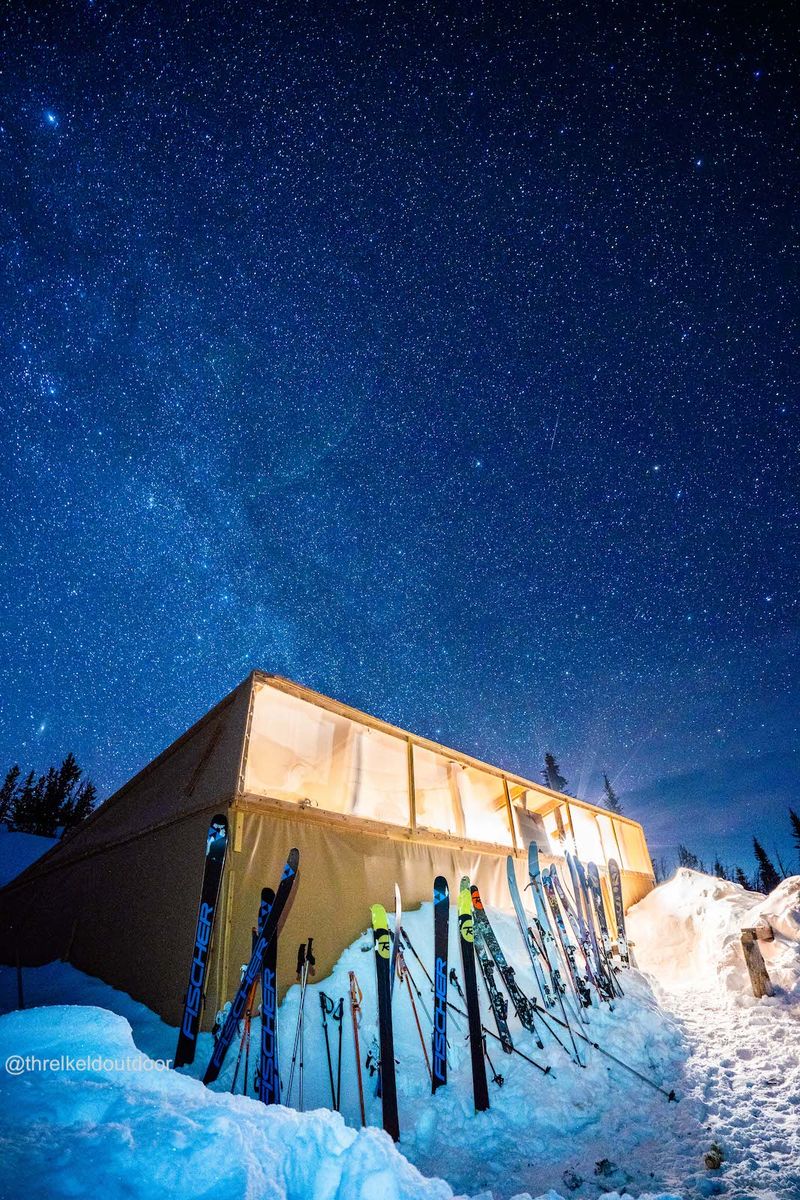 Big Belt Hut under the stars at night with skis lined up outside