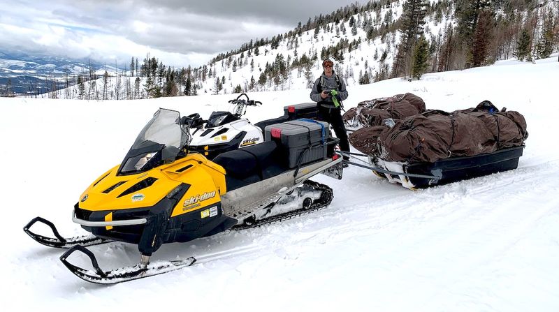 Snowmobiles hauling guests and gear